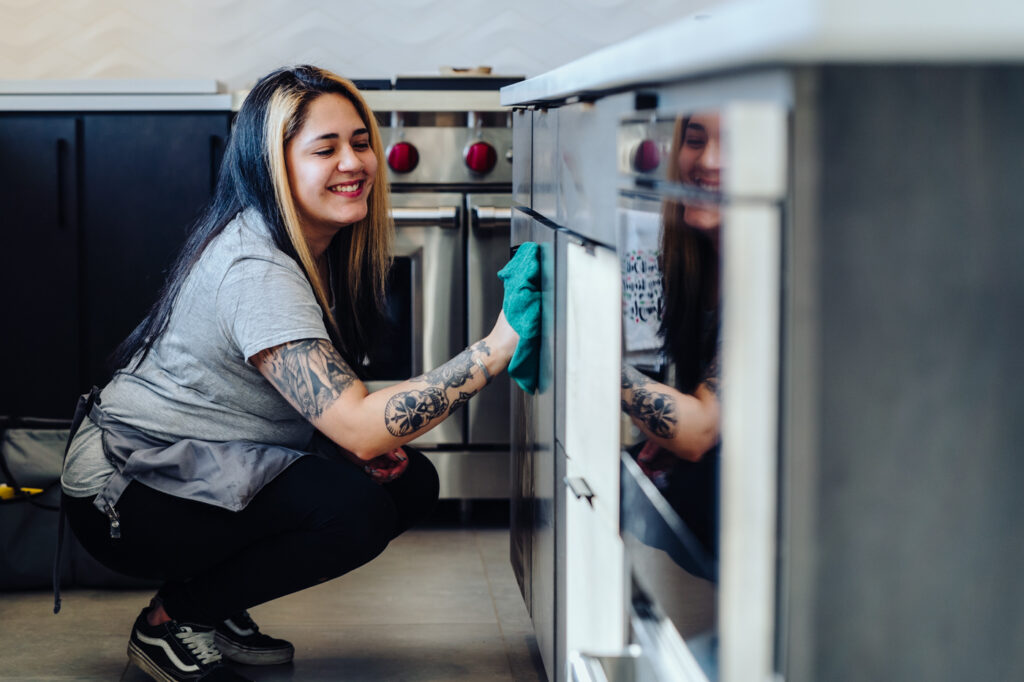 Landers employee wiping the front of a stove smiling