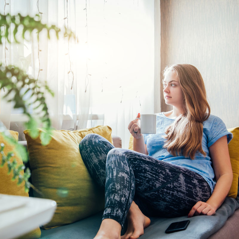 woman relaxing on sofa drinking tea